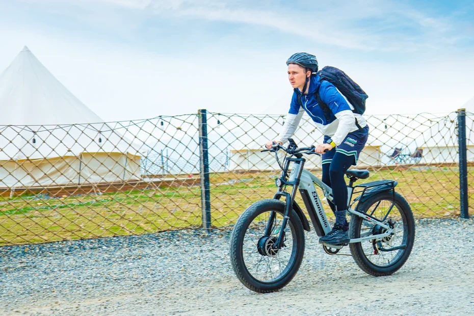 A model is cycling on the Shengmilo S600 electric bike in a beautiful outdoor setting.